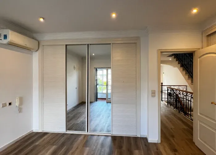 Freshly painted white bedroom with a mirrored wardrobe